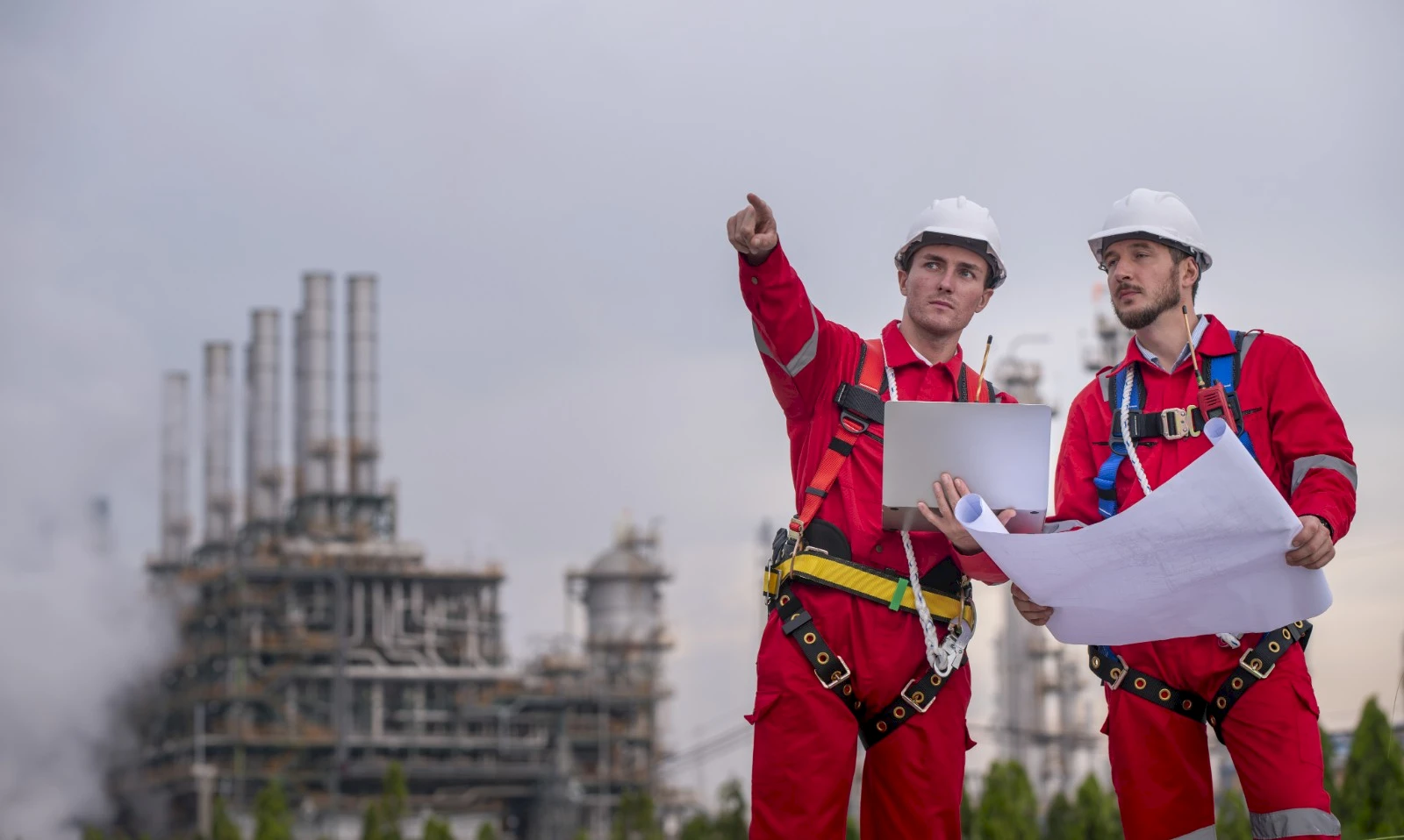 Oil and gas workers reviewing compliance plans at a refinery